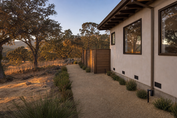 A hardened California home with a clean five-foot perimeter and noncombustible materials near the foundation at golden hour.